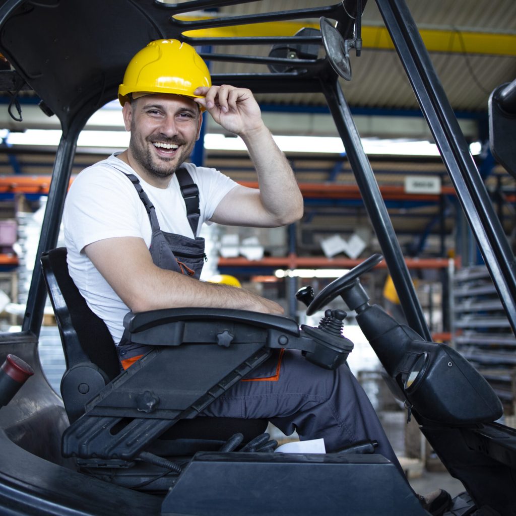 Portrait of smiling professional forklift driver in factory's warehouse.